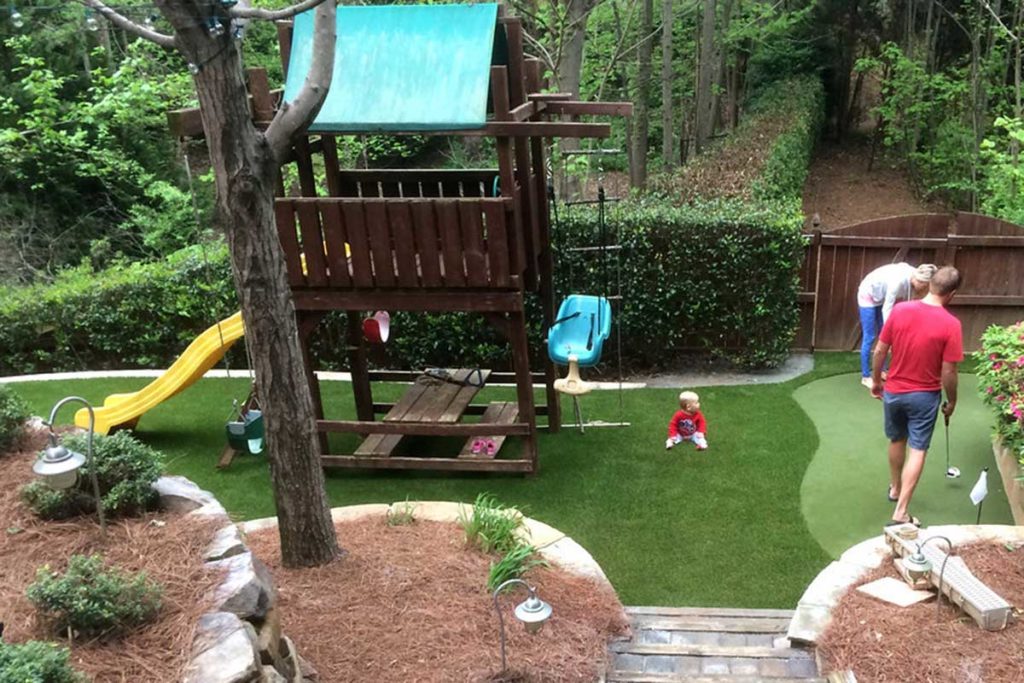 an artificial grass playground and putting green in a backyard